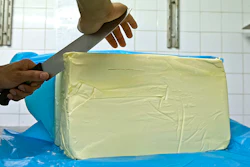 French baker Stephane Louvard puts his hand on a slice of butter in his Paris bakery, Friday, Oct.20, 2017. French pastries and butter have become so popular abroad that the increased demand led to a mini shortage of the dairy product in French supermarkets. (AP Photo/Bertrand Combaldieu)