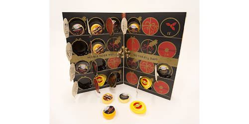 In this Oct. 23, 2018, photo a cheese advent calendar from England's Ilchester Cheese Company is displayed in New York. The cardboard calendars, typically filled with chocolates, are now being stuffed with cans of beer, bottles of wine and chunks of cheese. The companies behind them say they appeal to nostalgic adults who want to count the days till Christmas with something other than sweets. (AP Photo/Mark Lennihan)
