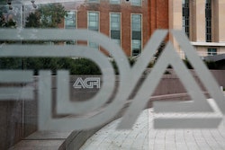 This Aug. 2, 2018, file photo shows the U.S. Food and Drug Administration building behind FDA logos at a bus stop on the agency's campus in Silver Spring, Md. The U.S. government isn’t doing routine food inspections because of the partial federal shutdown, but checks of the riskiest foods are expected to resume next week. The FDA said Wednesday, Jan. 9, 2019, that it's working to bring back about 150 employees to inspect riskier foods such as cheese, infant formula and produce. (AP Photo/Jacquelyn Martin, File)