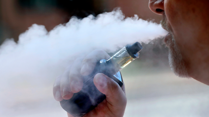 In this Aug. 28, 2019 file photo, a man exhales while smoking an e-cigarette in Portland, ME.