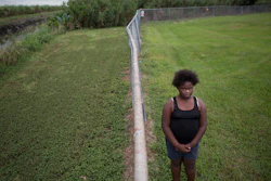 In this Nov. 4, 2019 photo, Kaniyah Patterson stands in front of a sugar cane field behind her home in Pahokee, FL.