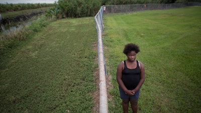In this Nov. 4, 2019 photo, Kaniyah Patterson stands in front of a sugar cane field behind her home in Pahokee, FL.
