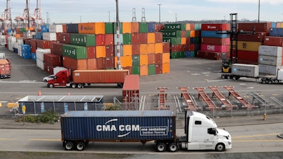 In this Oct. 2, 2019 file photo, trucks hauling shipping containers drive near containers stacked five-high at a terminal on Harbor Island in Seattle. US and China are trying to finalize a modest trade agreement to deescalate a trade war that has rattled financial markets and hobbled global economic growth.