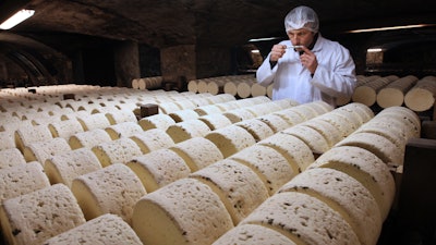 In this Jan. 21, 2009 file photo, Bernard Roques, a refiner of Societe company, smells a Roquefort cheese as they mature in a cellar in Roquefort, southwestern France.