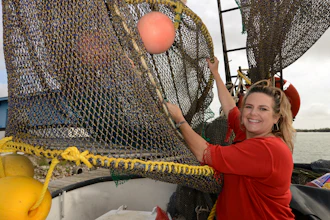 In this Dec. 5, 2014 file photo, Andrea Hance, Texas Shrimp Association executive director, poses with a TED, or turtle excluder device, on board a shrimp boat at the Brownsville Shrimp Basin in Brownsville, TX.