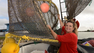 In this Dec. 5, 2014 file photo, Andrea Hance, Texas Shrimp Association executive director, poses with a TED, or turtle excluder device, on board a shrimp boat at the Brownsville Shrimp Basin in Brownsville, TX.