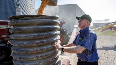 In this July 12, 2018 file photo, farmer Don Bloss checks on the operation of an auger transferring corn on his farm in Pawnee City, NE.