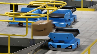 In this Dec. 17 photo, an Amazon robot sends a package down a chute, transporting packages from workers to chutes that are organized by zip code, at an Amazon warehouse facility in Goodyear, AZ. The tech giant is still rolling out new models descended from the Kiva line, including the Pegasus, a squarish vehicle with a conveyor belt on top that can be found working the early-morning shift at a warehouse in the Phoenix suburb of Goodyear.