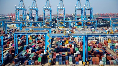In this Thursday, Nov. 28, 2019, photo, trucks load containers at the automated container dockyard in Qingdao in east China's Shandong province. A Chinese official newspaper has reiterated, repeatedly, Beijing's demand that the U.S. roll back tariffs imposed by President Donald Trump's administration in exchange for a deal. The Communist Party newspaper Global Times ran several articles Monday, Dec. 2, 2019 that emphasized there would be no deal without a promise to phase out the tariffs imposed by Washington.