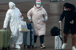 A passenger wearing a full-body protective suit catches the eyes of others as they walk out from the Beijing railway station in Beijing on Tuesday, Feb. 11. China's daily death toll from a new virus topped 100 for the first time and pushed the total past 1,000 dead, authorities said Tuesday after leader Xi Jinping visited a health center to rally public morale amid little sign the contagion is abating.