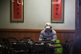 In this Feb. 13 photo, Frankie Chu, owner of Vegetarian Dim Sum House in New York's Chinatown, sits in his empty restaurant usually bustling with customers, in New York. Sales have plunged 70% over the last two weeks, 'I don't know how long I can stay here,' Chu said. 'After 9/11, it wasn't this bad.'