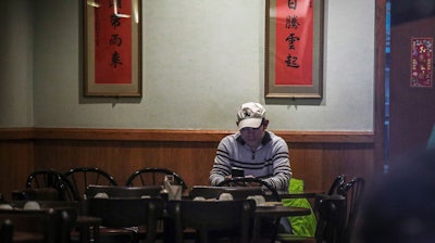 In this Feb. 13 photo, Frankie Chu, owner of Vegetarian Dim Sum House in New York's Chinatown, sits in his empty restaurant usually bustling with customers, in New York. Sales have plunged 70% over the last two weeks, 'I don't know how long I can stay here,' Chu said. 'After 9/11, it wasn't this bad.'