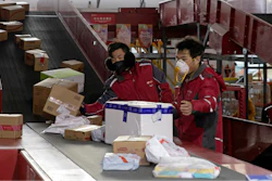 In this Tuesday, Feb. 18, 2020, photo, delivery workers for Chinese e-commerce giant JD.com sort out parcels at a distribution center in Beijing, China.