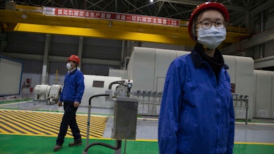 Workers stand in the generator room at the Huadian Beiran Corporation's power plant in Beijing on Thursday, Feb. 27. The state-owned company's steam and gas combined cycle power plant on the outskirts of the nation's capital, which opened in 2017 and provides electricity and heat to the Tongzhou District, managers have instituted virus prevention measures include masks, disinfection wipes, and measuring body temperature for employees entering the premises.