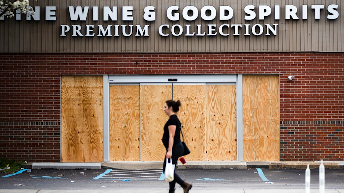 A pedestrian walks past a boarded up Wine and Spirits store in Philadelphia on Friday, March 20. Pennsylvania Gov. Tom Wolf directed all 'non-life-sustaining' businesses to close their physical locations late Thursday and said state government would begin to enforce the edict starting early Saturday.