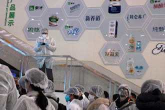 In this Thursday, Feb. 27 photo, journalists dressed in protective overalls visit the Mengniu dairy factory in Beijing. Reporters were invited to China Mengniu Dairy Co. Ltd. last week to be shown how companies are reviving after anti-virus measures shut down most of the world's second-biggest economy.