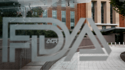 U.S. Food and Drug Administration building behind FDA logos at a bus stop on the agency's campus in Silver Spring, Md.