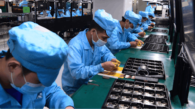 In this Feb. 13, 2020, photo released by Xinhua News Agency, workers wearing masks labor at a factory for Chinese telecommunications company OPPO.