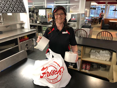 In this photo made on March 20, Frisch's Big Boy restaurant employee Nicole Cox bags up an order of toilet paper, among in-demand items including milk and bread the double-decker burger chain is now offering during the coronavirus outbreak in Cincinnati, OH.
