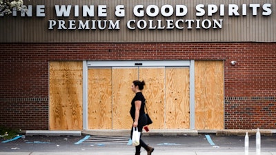 A pedestrian walks past a boarded up Wine and Spirits store in Philadelphia on Friday, March 20. Pennsylvania Gov. Tom Wolf directed all 'non-life-sustaining' businesses to close their physical locations late Thursday and said state government would begin to enforce the edict starting early Saturday.