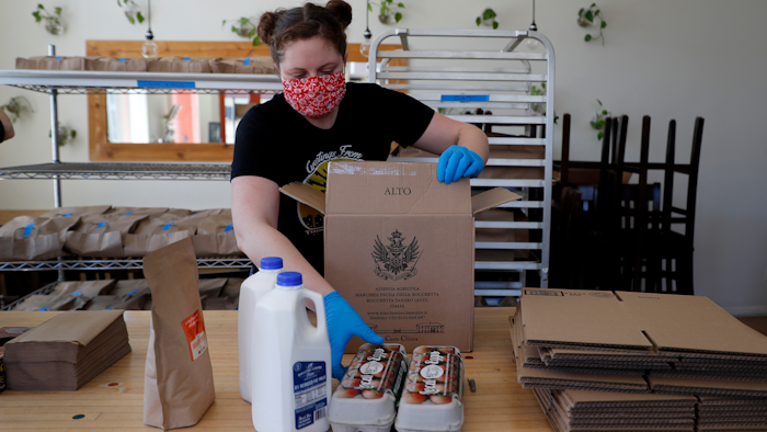 Monica Mileur packs grocery items into a box at Union Loafers restaurant on Friday, April 10 in St. Louis. Some restaurants have turned to selling groceries and other provisions to customers as a way to help make up for revenue lost during the coronavirus outbreak.
