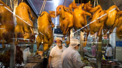 In this Wednesday, Nov. 11, 2015, photo, a worker prepares cooked ducks for sale at a Wal-Mart in Shenzhen, in southern China's Guangdong province. If Arkansas-based Wal-Mart wants to win over foreign consumers, it has to shed some of its American ways, and cater to very different customs and conventions. China is the ultimate prize.
