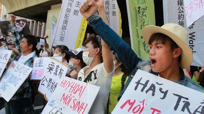Vietnamese activists shout slogans and hold placards reading ''Destroying the environment is killing, 'left, and ''Return clean seawater to us'' during a protest to urge Formosa Plastics Group to take responsibilities for the cleanup in Vietnam, in Taipei, Taiwan.