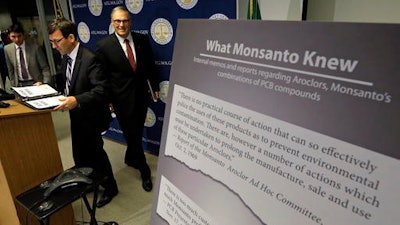 Washington Attorney General Bob Ferguson, left, and Gov. Jay Inslee head into a news conference where Ferguson announced a lawsuit against agrochemical giant Monsanto over pollution from PCBs, Thursday, Dec. 8, 2016, in Seattle. Washington says it's the first U.S. state to sue Monsanto over pollution from PCBs. The chemicals, polychlorinated biphenyls, were used in many industrial and commercial applications, including in paint, coolants, sealants and hydraulic fluids. PCB contamination impairs rivers, lakes and bays around the country.
