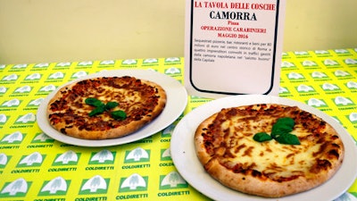 Pizzas are displayed near a sign listing the police operations against restaurants and bars owned by the Camorra crime syndicate, during a report on organized crime infiltration in Italy's much prized food and agriculture businesses at the Coldiretti, the Italian farmers association headquarters in Rome, Tuesday, March 14, 2017. Organized crime has a seemingly insatiable appetite for farm and food businesses, one of the few economic sectors experiencing growth during Italy's protracted economic crisis.