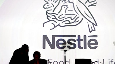 In this April 7, 2016 file photo Nestle's directors speak in front of the Nestle's logo during the general meeting of Nestle Group, in Lausanne, Switzerland. The world’s biggest food and drinks company, Nestle, says it is buying husband-and-wife startup Sweet Earth, which sells frozen burritos stuffed with quinoa, beans and other vegetarian ingredients. .