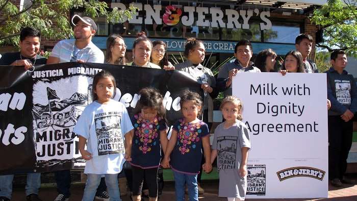 Children stand in front of a banner commemorating an agreement signed by ice cream maker Ben & Jerry's and immigrant farm workers, Tuesday, Oct. 3, 2017, in Burlington, Vt. The agreement promotes the rights of immigrant farm workers while paying more to the farmers who employ them. The company and the workers said it's the first agreement of its kind in the dairy industry.