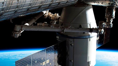 1 0 In this image provided by NASA, the Dragon capsule arrives at the International Space Station on Wednesday, April 4, 2018 with food and experiments. It will remain attached to the orbiting outpost for about a month, returning to Earth in May. Dragon launched Monday from Cape Canaveral, Florida, aboard a used Falcon rocket. SpaceX wants to reduce launch costs by recycling rocket parts.