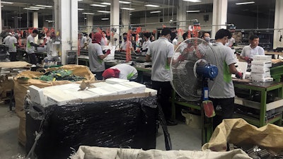 In this photo taken Thursday, May 24, 2018, and released by the Royal Thai Police, factory workers process electronic waste in Lat Krabang, outside Bangkok, Thailand. Police have raided several factories near Bangkok that allegedly were processing illegally imported electronic waste in a sign that China’s crackdown on waste recycling is pushing such operations offshore.