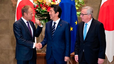 Japanese Prime Minister Shinzo Abe, center, shakes hands with European Council President Donald Tusk next to European Commission President Jean-Claude Juncker, right, before a meeting at Abe's official residence in Tokyo Tuesday, July 17, 2018. The European Union and Japan are signing a widespread trade deal Tuesday that will eliminate nearly all tariffs, seemingly defying the worries about trade tensions set off by U.S. President Donald Trump's policies.