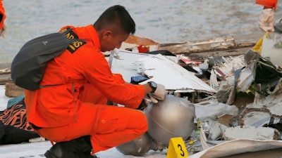 A member of Indonesian National Search and Rescue Agency (BASARNAS) inspects debris recovered from the area where a Lion Air passenger jet is suspected to crash, at Tanjung Priok Port in Jakarta, Indonesia Monday, Oct. 29, 2018. A Lion Air flight crashed into the sea just minutes after taking off from Indonesia's capital on Monday in a blow to the country's aviation safety record after the lifting of bans on its airlines by the European Union and U.S.