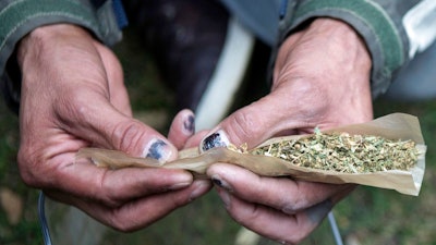 A man rolls a large joint in a Toronto park on Wednesday, Oct. 17, 2018. Canada became the largest country with a legal national marijuana marketplace as sales began early Wednesday.