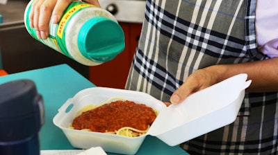 In this Thursday, March 14, 2019 photo, Belinda Lau, manager of the Wiki Wiki Drive Inn takeout restaurant in Honolulu, sprinkles cheese on an order of spaghetti in a styrofoam container. Hawaii would be the first state in the U.S. to ban most plastics used at restaurants under legislation that aims to cut down on waste that pollutes the ocean. Dozens of cities across the country have banned plastic foam containers, but Hawaii would be the first to bar them statewide.