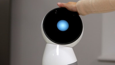 In this Nov. 21, 2017, file photo Massachusetts Institute of Technology professor and robotics researcher Cynthia Breazeal reaches to touch social robot Jibo at the company's headquarters in Boston. When robots move like humans and talk like humans, even if only a little bit, it’s natural that we will treat them more like humans.
