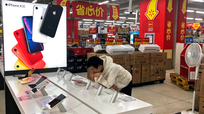 A man browses an iPhone unit on display at a section selling Apple's products together with Chinese made electric appliances at a hypermarket in Beijing, Thursday, May 9, 2019. Ratcheting up tension ahead of talks in Washington, China vowed Thursday to defend its own interests and retaliate if President Donald Trump goes ahead with more tariff hikes in a dispute over trade and technology.