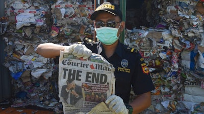 Indonesian custom officers show off the front of a foreign newspaper amoung waste found in a container at the Tanjung Perak port in Surabaya, East Java, Indonesia, Tuesday, July 9, 2019. Indonesia is sending dozens of containers of imported waste back to Western nations after finding it was contaminated with used diapers, plastic and other materials, adding to a growing backlash in Southeast Asia against being a dumping ground for the developed world's rubbish.