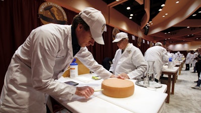 Judge Douwe Dijkstra pulls out a piece of Appenzeller cheese at the biennial World Championship Cheese Contest, Tuesday, March 3, 2020, at the Monona Terrace Convention Center in Madison, Wis.
