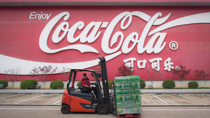 In this March 24 photo released by China's Xinhua News Agency, a worker wearing a face mask drives a forklift at a Swire Coca-Cola Beverages Hubei Limited plant in Wuhan in central China's Hubei Province. According to Chinese state media, the plant restarted some production lines on Monday.