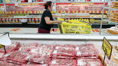 Amid concerns of the spread of COVID-19, a shopper wears a mask as she walks through the meat products at a grocery store in Dallas on Wednesday, April 29.