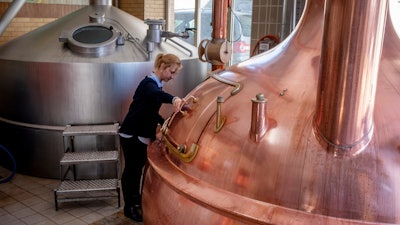 In this Friday, April 17 photo, junior director Christine Lang of the 'Wernecker brewery' stands in the brewhouse of the brewery in Werneck, Germany. Due to the impact of the coronavirus the traditional brewery has to close 400 years after its foundation. (AP Photo/Michael Probst).