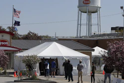 Workers wait in line to enter the Tyson Foods pork processing plant in Logansport, IN on Thursday, May 7. The plant was expected to open Thursday after closing on April 25 after nearly 900 employees tested positive for the coronavirus.