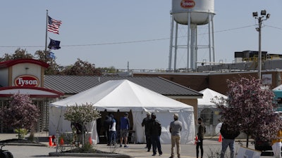 Workers wait in line to enter the Tyson Foods pork processing plant in Logansport, IN on Thursday, May 7. The plant was expected to open Thursday after closing on April 25 after nearly 900 employees tested positive for the coronavirus.