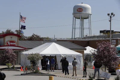 Workers wait in line to enter the Tyson Foods pork processing plant in Logansport, IN on Thursday, May 7. The plant was expected to open Thursday after closing on April 25 after nearly 900 employees tested positive for the coronavirus. Workers won't be able to return to work until they get tested.