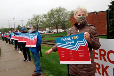 Sioux Falls resident Pat Lloyd, right, waves to greet employees of a Smithfield pork processing plant as they begin their shift on Wednesday, May 20 in Sioux Falls, SD.