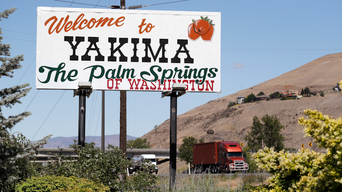 In this photo taken June 17, a sign declares off the highway in Yakima, Wash., declares the city the 'Palm Springs of Washington.' The coronavirus pandemic is hitting Yakima County hard, with cases surging far faster in than in the rest of the state. The virus has caused turmoil in the farm and food processing industries, where some fearful workers staged wildcat strikes recently to demand that employers provide safer working conditions.