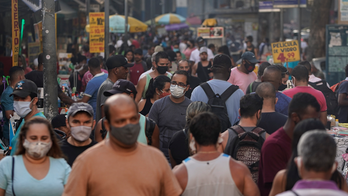 Pedestrians, some wearing protective face masks, walk through a street market in downtown Rio de Janeiro, Brazil on June 25.